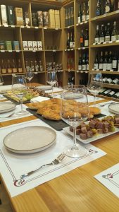 Mesa preparada para la cata con tabla de quesos, empanadas y brochetas de atún, junto a copas de vino